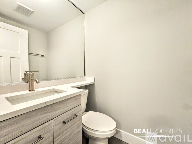 A spacious room with wooden flooring and a window with blinds.