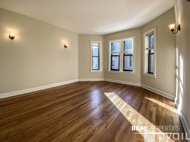 A room with wooden flooring and two windows.
