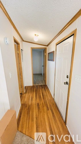 A hallway with a wooden floor and white walls.