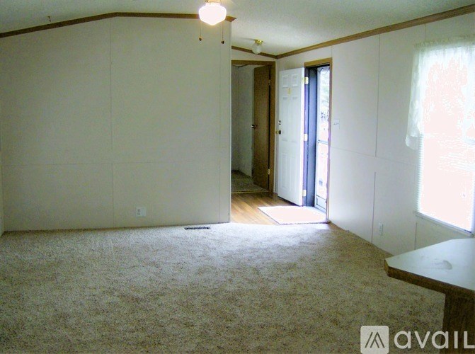 A room with a carpeted floor and a window with curtains.