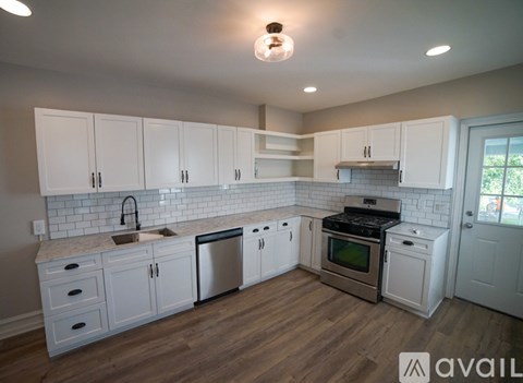 A kitchen with white cabinets and a wooden floor.