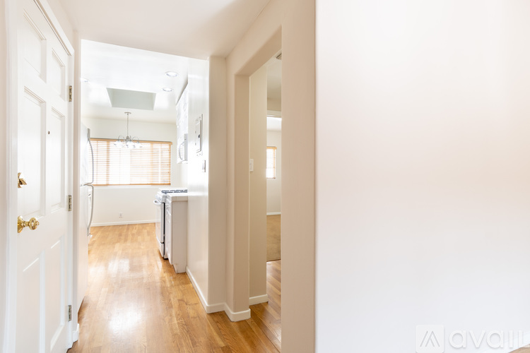 A hallway with a white door on the left and a white wall on the right.