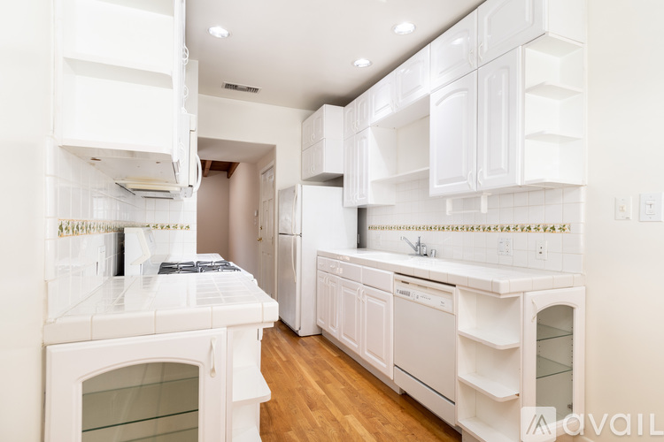 A white kitchen with wooden floors and white appliances.