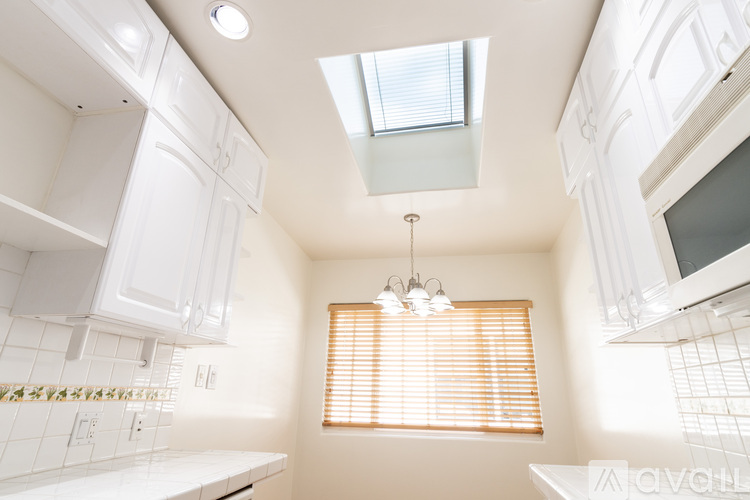 A kitchen with white cabinets and a skylight.