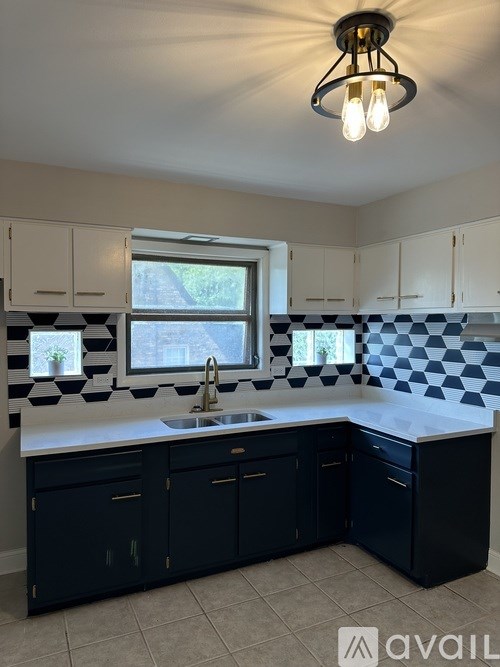A kitchen with black cabinets and a checkered backsplash.