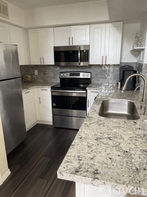 A kitchen with a granite counter top and stainless steel appliances.