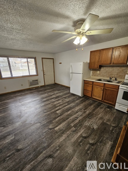 A kitchen with wooden floors and white appliances.