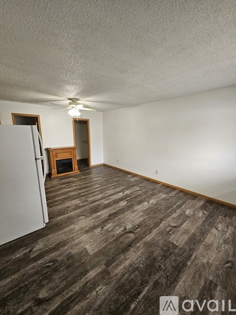 A room with a wooden floor and a white refrigerator.