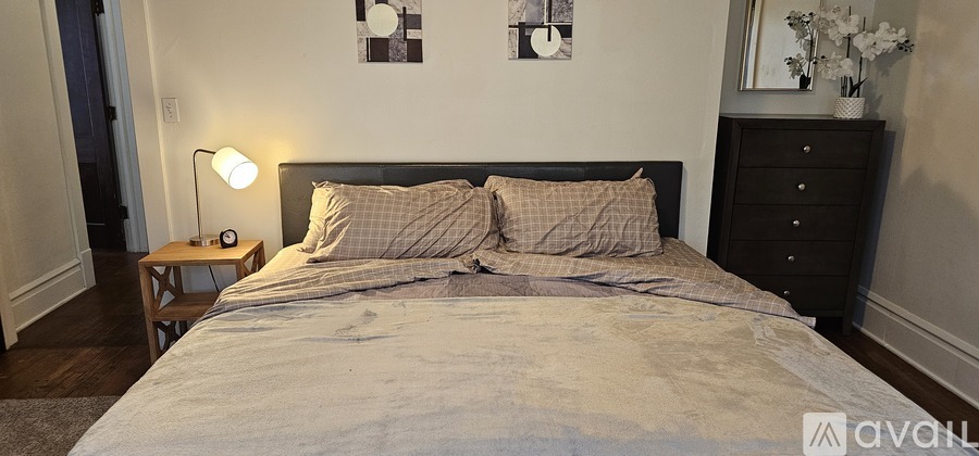 A bedroom with a large bed and a nightstand with a lamp.