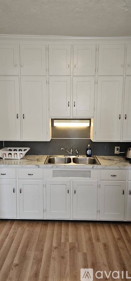 A kitchen with white cabinets and a wooden floor.