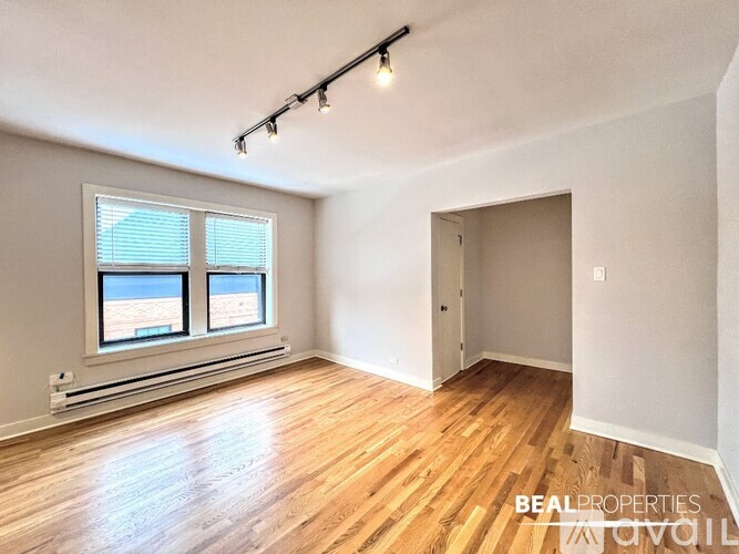 A room with wooden floors and white walls is available for rent.
