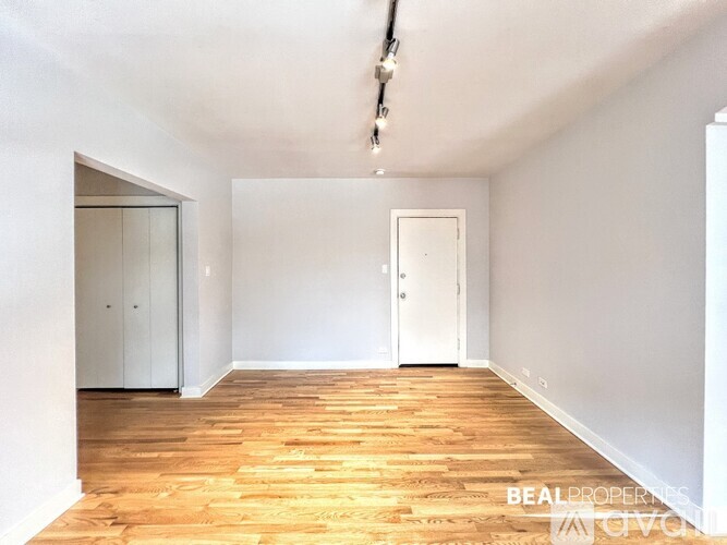 A room with a white door and a wooden floor.
