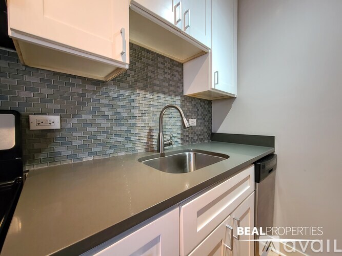 A modern kitchen with a stainless steel sink and white cabinets.