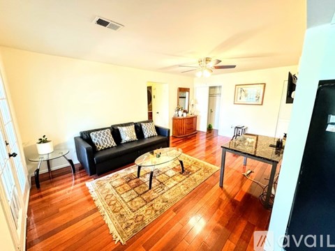 A living room with a black couch and a rug.