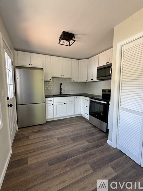 A kitchen with white cabinets and a wooden floor.