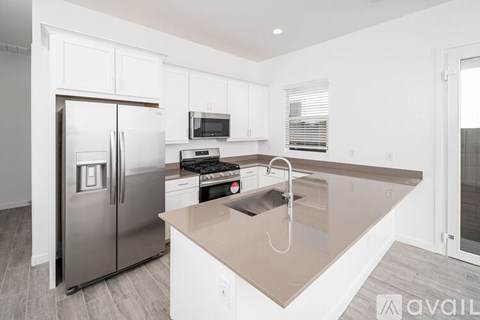 A kitchen with a refrigerator, microwave, and stove top oven.