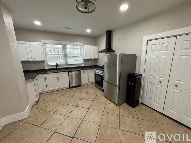 A kitchen with a stainless steel refrigerator and a black trash can.
