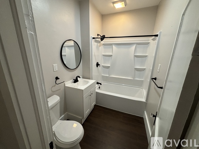 A small white bathroom with a toilet, sink, and a mirror.
