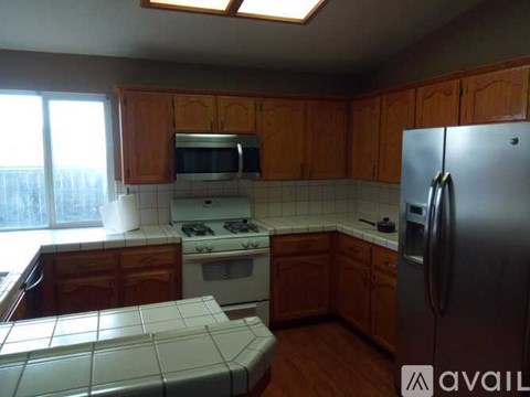 A kitchen with wooden cabinets and a stainless steel refrigerator.