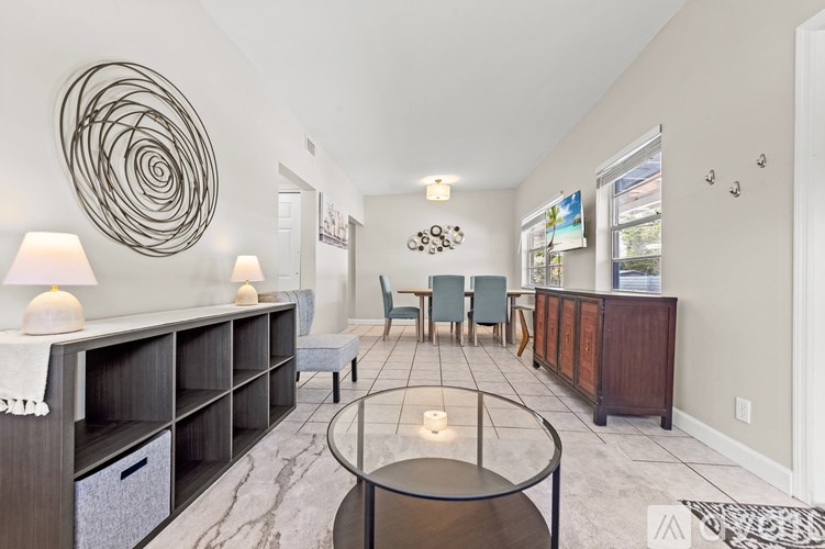 A living room with a red couch, a glass table, and a white door.