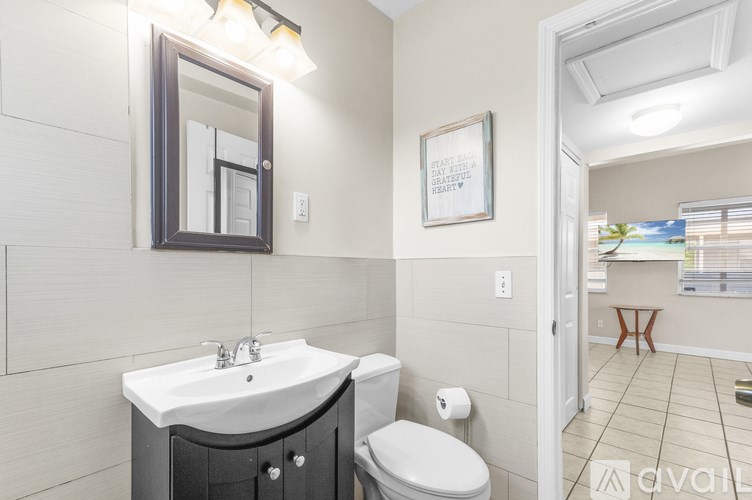 A bathroom with a toilet, sink, and mirror.
