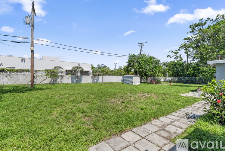 A backyard with a grassy area, a concrete path, and a utility pole.