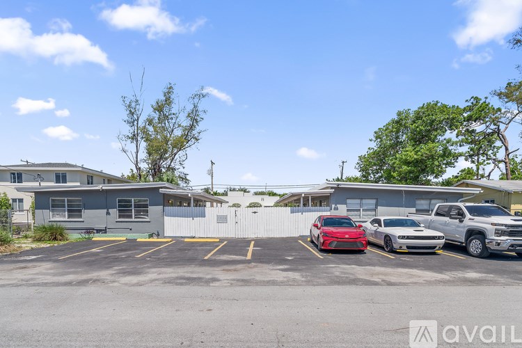 A parking lot with a red car in the foreground and a silver car and a white truck in the background.