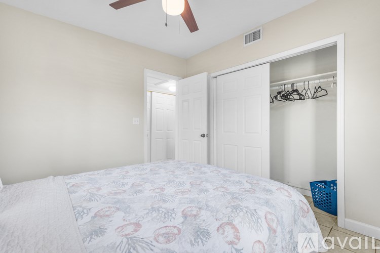 A bedroom with a bed, a ceiling fan, and a closet.