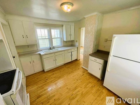 A kitchen with white cabinets and a wooden floor.