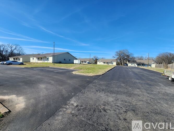 A parking lot with a building in the background on a sunny day.