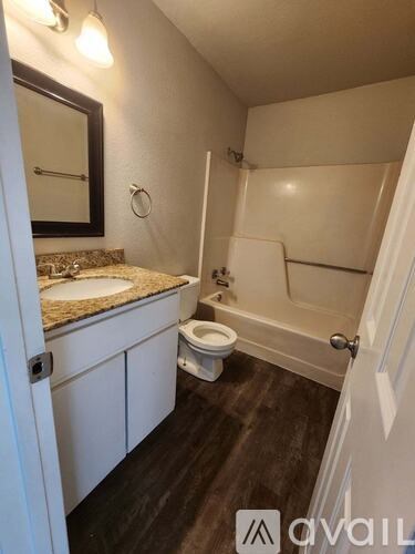 A bathroom with a toilet, sink, and mirror.