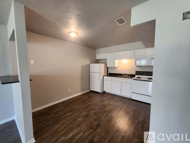 A kitchen with white appliances and wooden floors.