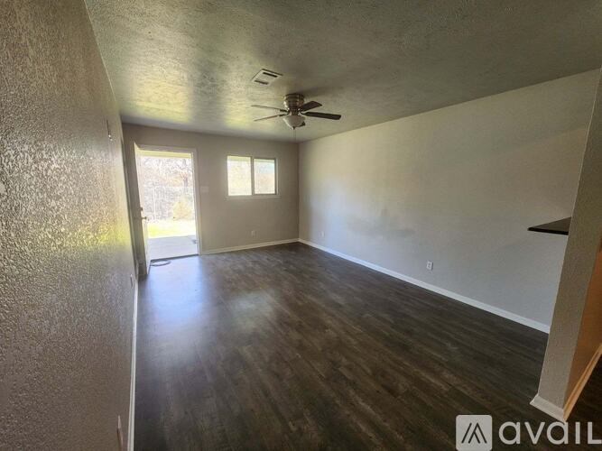 A room with a ceiling fan and wooden flooring.