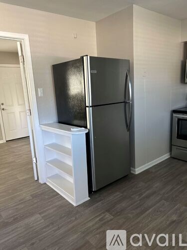 A black fridge with a white door and a white shelf unit.