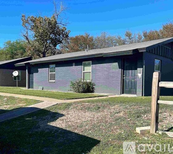A house with a grey roof and a small tree in front.