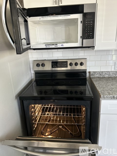 A black oven with the door open is in a kitchen.