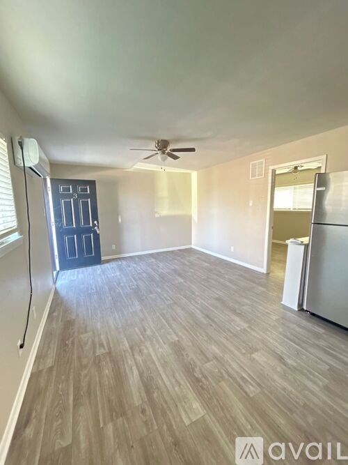 A room with a ceiling fan and a door on the left.