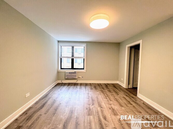 A spacious room with wood flooring and a single light fixture on the ceiling.