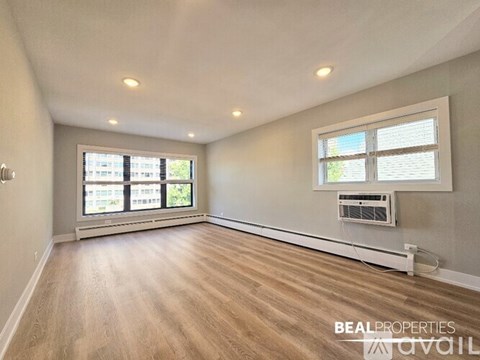 A room with wooden flooring and a window with blinds.