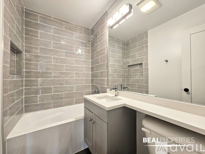 A spacious room with wooden flooring and two windows with blinds.