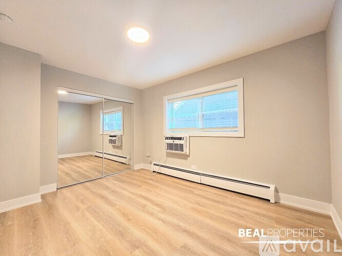 A spacious room with a window, a mirror, and a wall-mounted air conditioner unit.