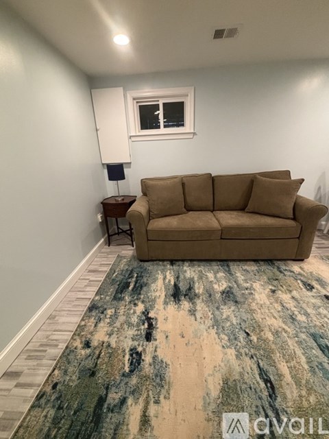 A living room with a brown couch and a blue rug.