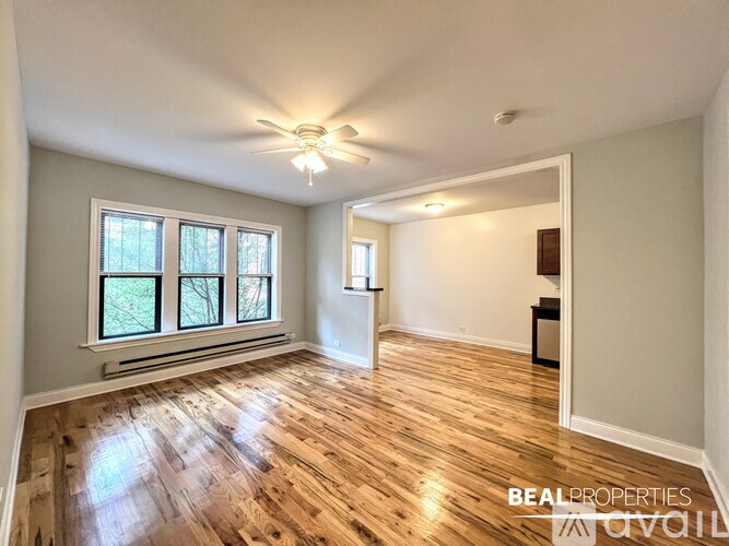 A spacious room with wooden flooring and a ceiling fan.