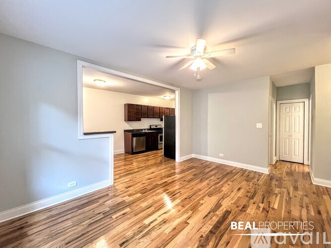 A spacious room with wooden flooring and a ceiling fan.