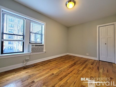 A white bedroom with a window and a wooden floor.