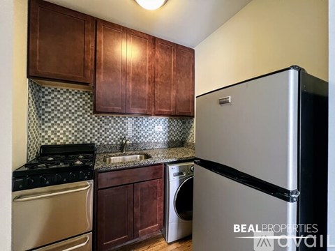 A kitchen with a black stove top oven, a black fridge, and a black and white checkered backsplash.