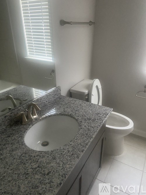 A bathroom with a granite countertop and a toilet.