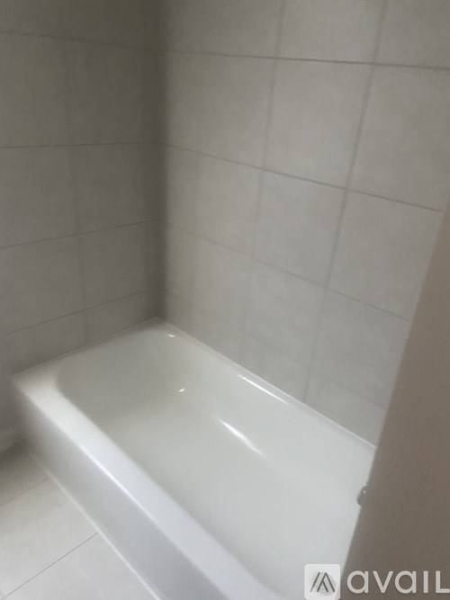 A white bathtub in a bathroom with white tiled walls.