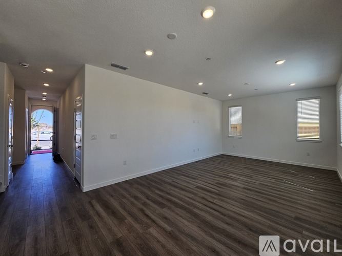 A spacious room with wooden flooring and white walls is available for rent.