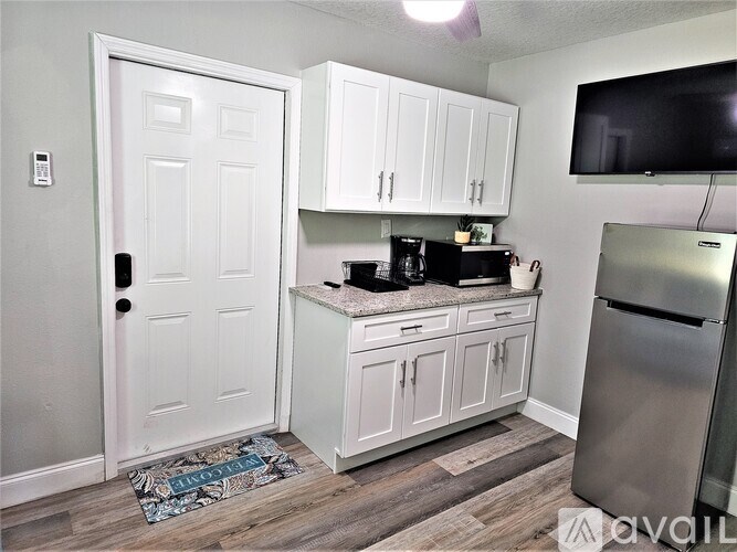 A kitchen with white cabinets and a white door.